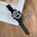 Casio G-Shock digital wristwatch with black strap, angled on white booklet