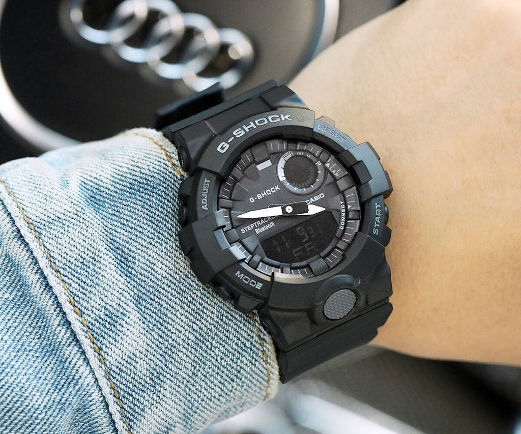 Casio G-Shock black-and-teal resin watch on wrist with circular digital face