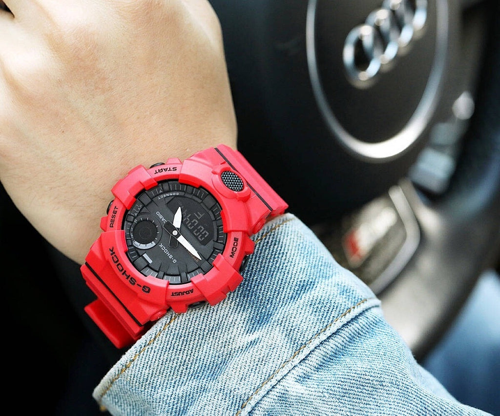 Casio watch with red resin strap and black dial on wrist.
