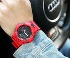 Casio watch with red resin strap and black dial on wrist.