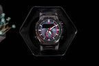 Black Casio watch in display box, round black case and blue-accented chronograph dial.
