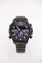Black Casio watch front view, blue patterned dial, red hands, black metal bracelet.