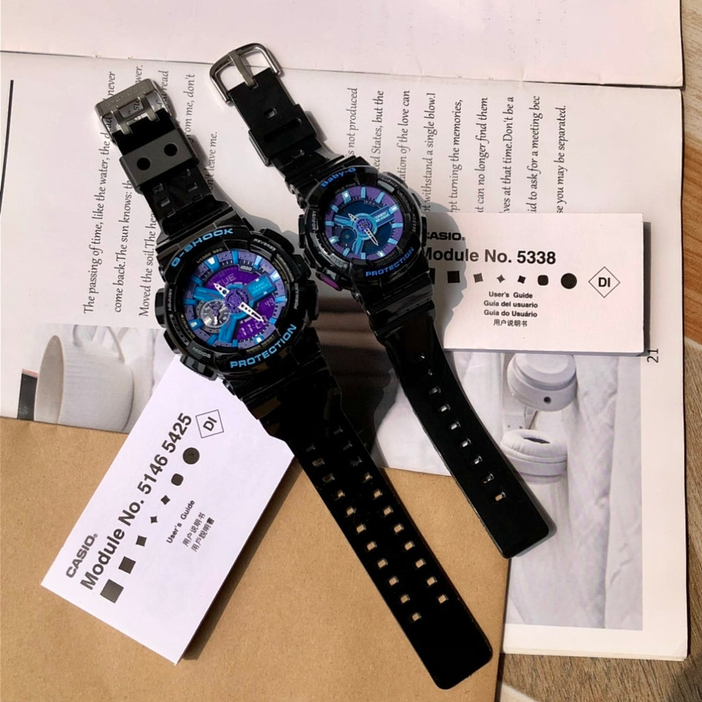 Two black G-Shock watches with perforated straps laid over paperwork and instruction sheets