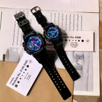 Two black G-Shock watches with perforated straps laid over paperwork and instruction sheets