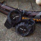 Two Casio watches with dark straps and round digital faces lying on pavement