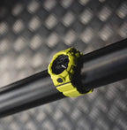 Casio watch with bright yellow strap and round digital face on a dark bar