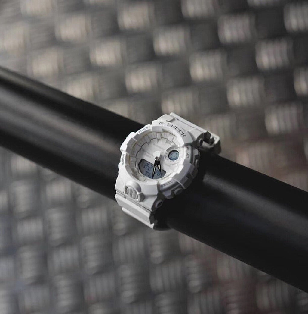 Casio watch with white bezel and round digital face on a dark cylindrical bar