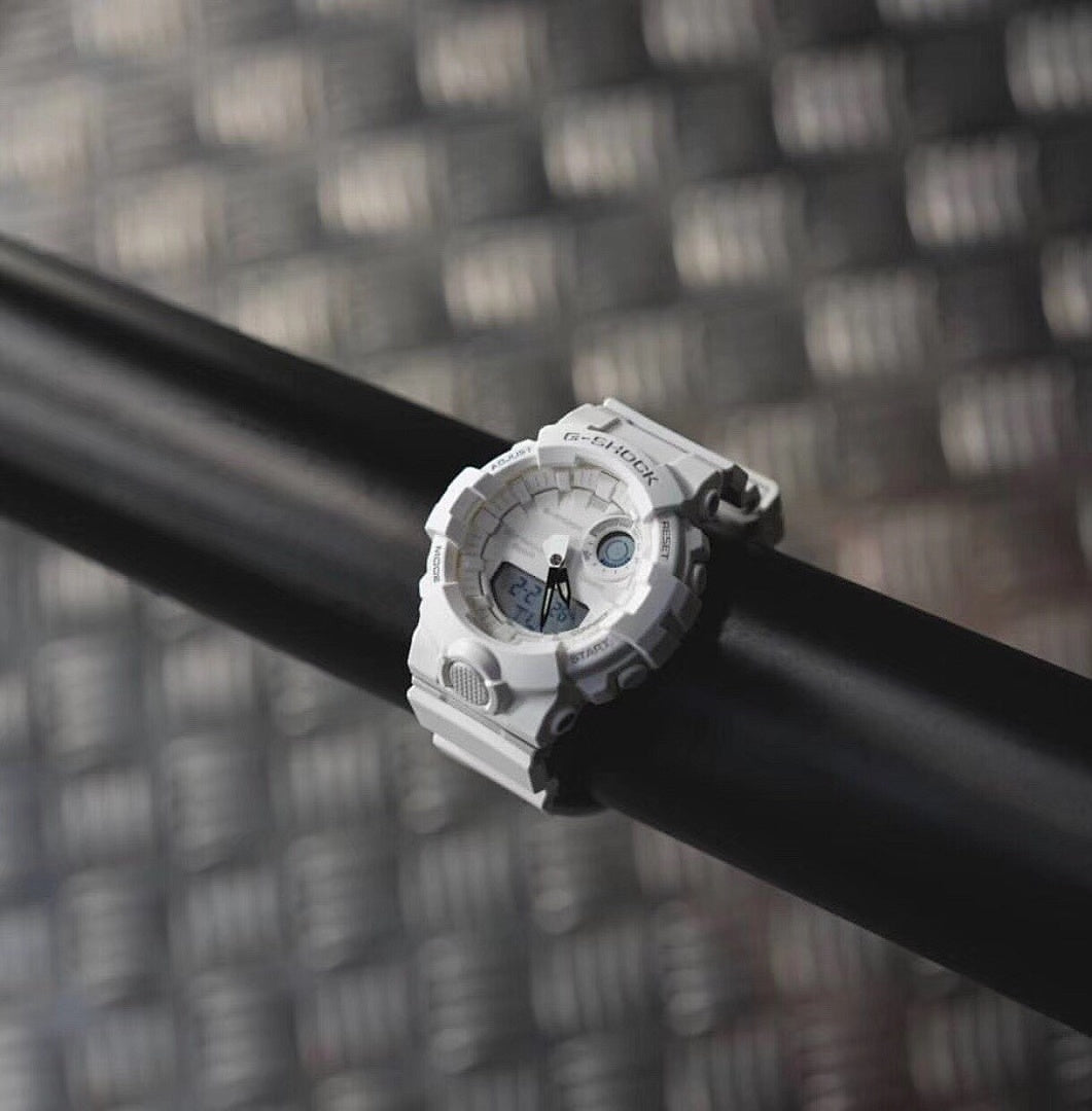 Casio watch with white bezel and round digital face on a dark cylindrical bar