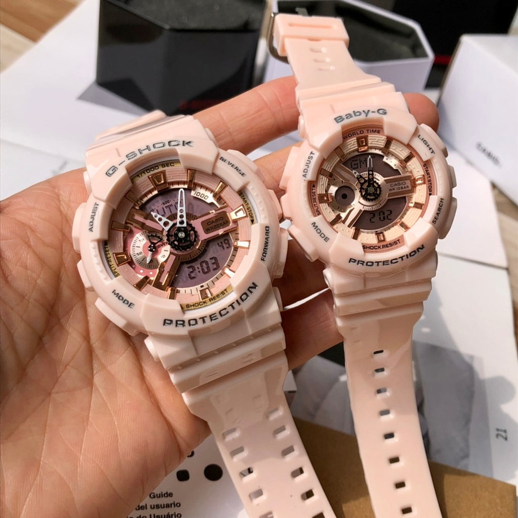 Two light pink resin wristwatches held in hand, featuring round multi-dial faces