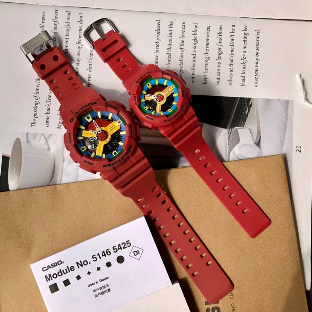 Two red Casio watches with long straps laid out on papers and a brown insert card