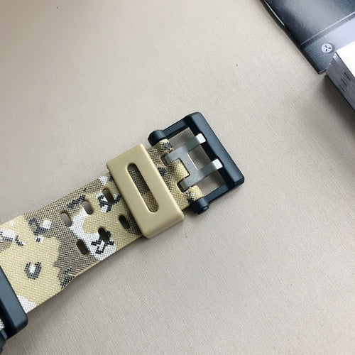 Camouflage fabric watch strap with black buckle and metal clasp.