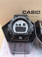 Casio G-Shock digital watch with silver face, black strap, and blue LCD readout
