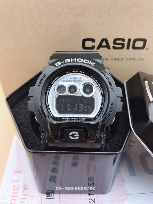 Casio G-Shock digital watch with silver face, black strap, and blue LCD readout