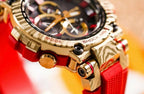 Casio G-Shock watch side close-up with red strap, gold-tone case details, black dial