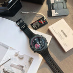 Casio Edifice wristwatch with black resin strap and dark dial, laid on box and papers