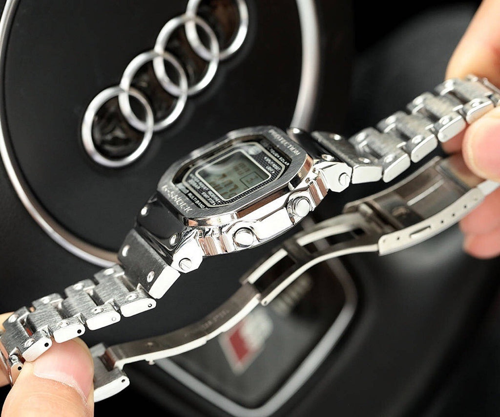 Silver-tone metal digital watch with bracelet extended in hand