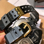 Casio G-Shock watch back and strap, black band with gold clasp hardware.