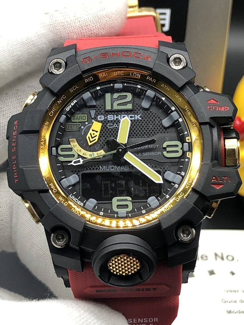 Casio sports watch, black case with gold rim, red band, analog-style dial close-up