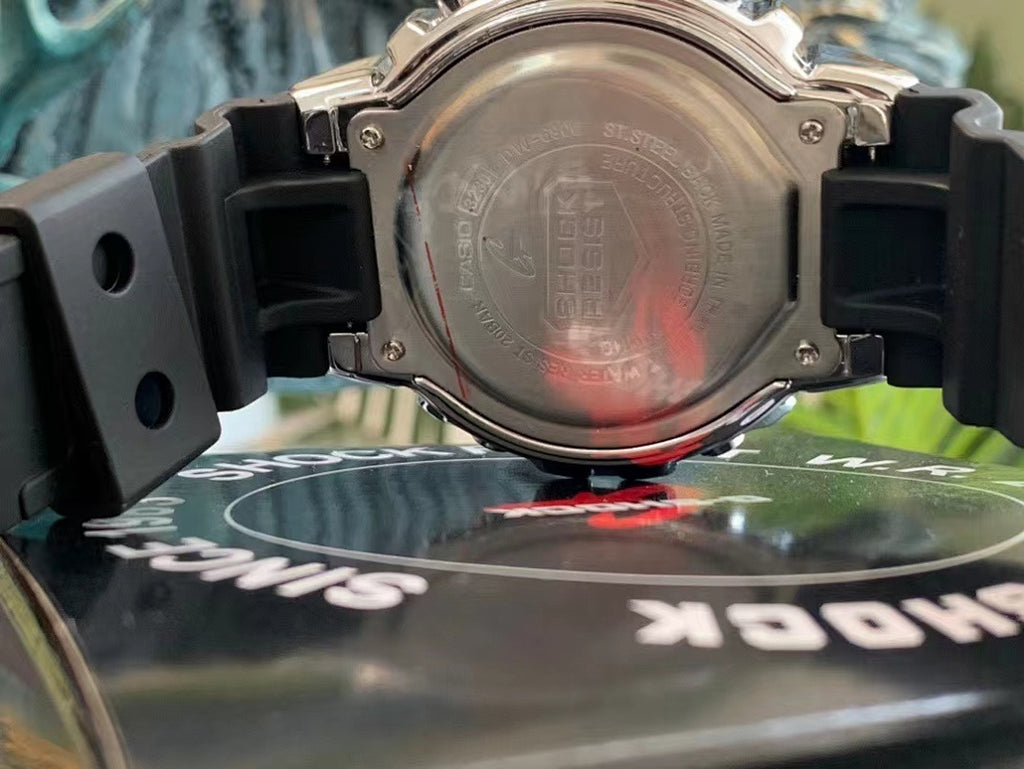 Silver digital watch case back with black rubber straps, engraved rear cover.