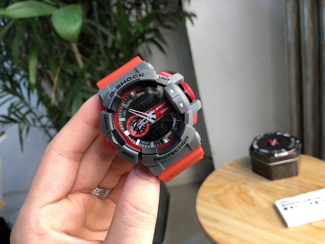 Casio watch held in hand with black dial, red highlights, and gray protective bezel