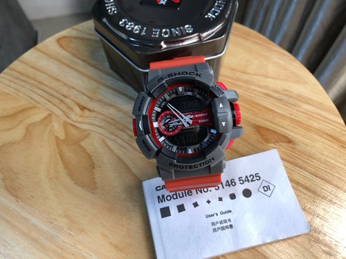 Casio watch front with black dial, red ring details, gray bezel and red strap