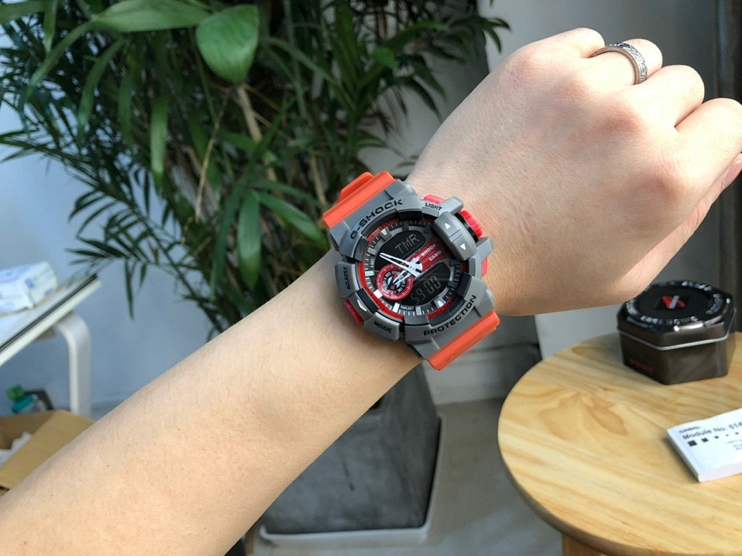 Casio watch on wrist with black face, red accents, gray case and red strap