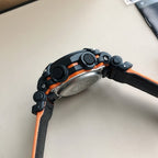 G-Shock wristwatch with black case, orange trim, textured strap, side view.