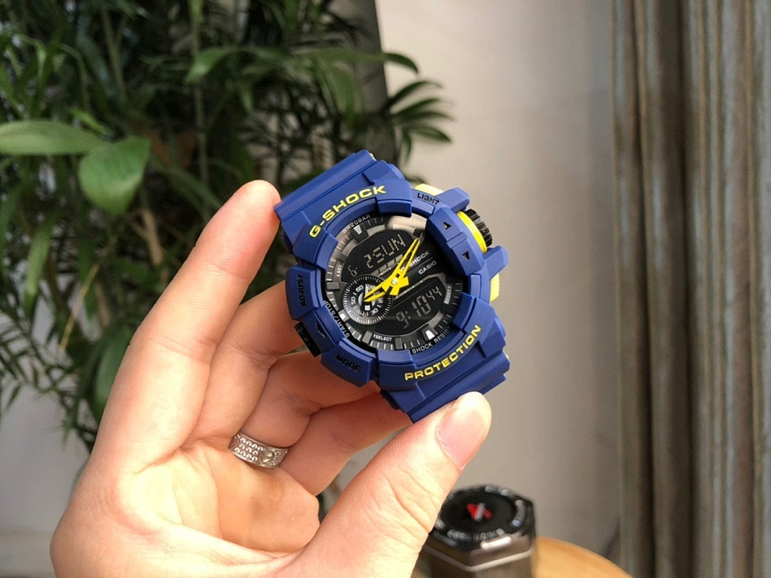 Casio G-Shock blue digital watch held in hand, black dial with yellow highlights