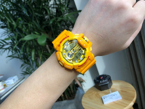 Casio watch with yellow resin strap on wrist, round digital face