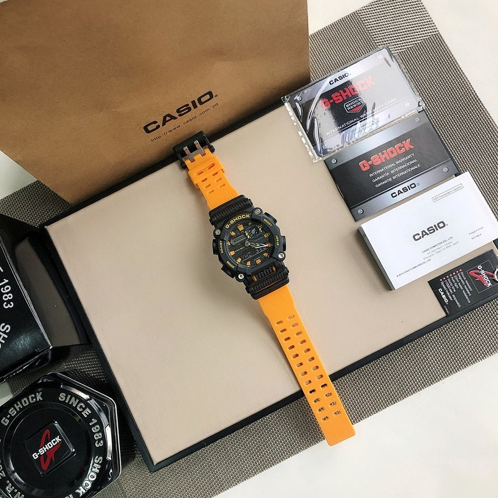 Casio G-Shock watch on bright orange resin strap, black bezel with dial markings.