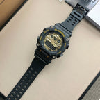 Casio G-Shock wristwatch with black strap and gold dial, orange bezel ring
