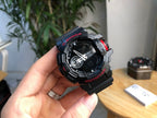 Casio G-Shock watch held in hand, black bezel with red accents and digital dial