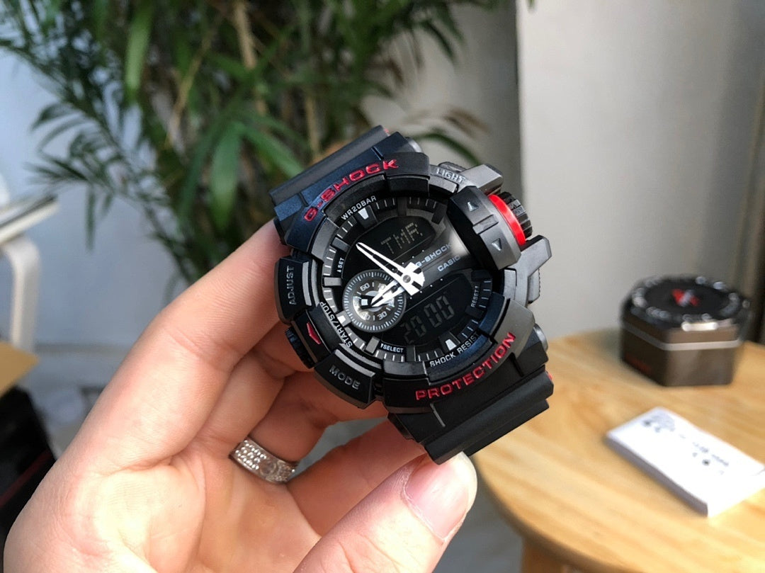 Casio G-Shock watch held in hand, black bezel with red accents and digital dial