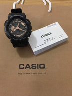 G-Shock watch with black resin strap and black dial, gold details.
