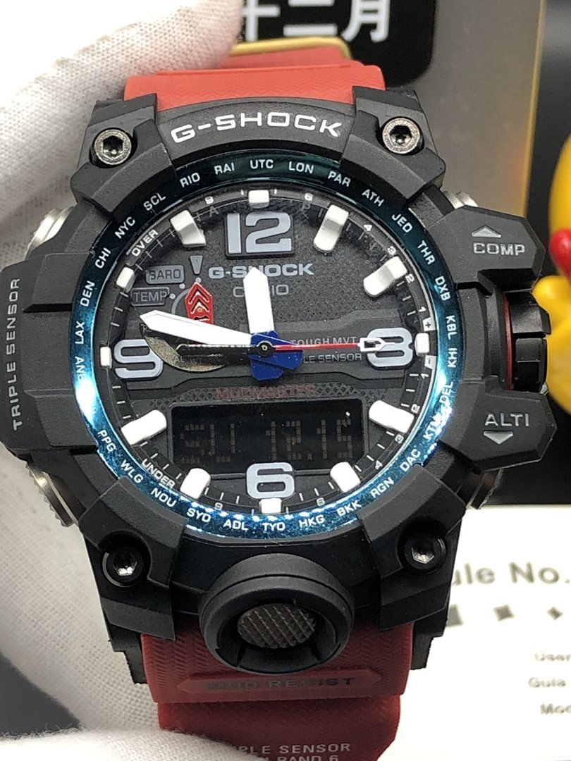 Casio G-Shock wristwatch close-up with black case, blue bezel accent, red strap