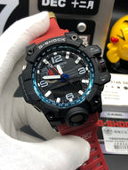 Casio G-Shock wristwatch with black case, red strap, and blue-accent bezel on hand
