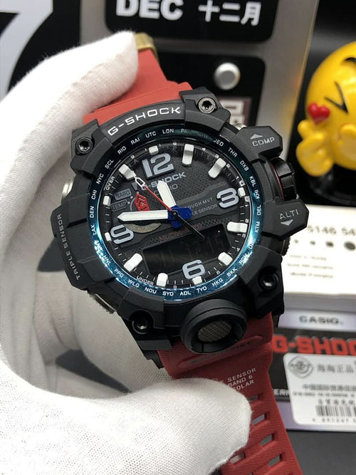 Casio G-Shock wristwatch with black case, red strap, and blue-accent bezel on hand