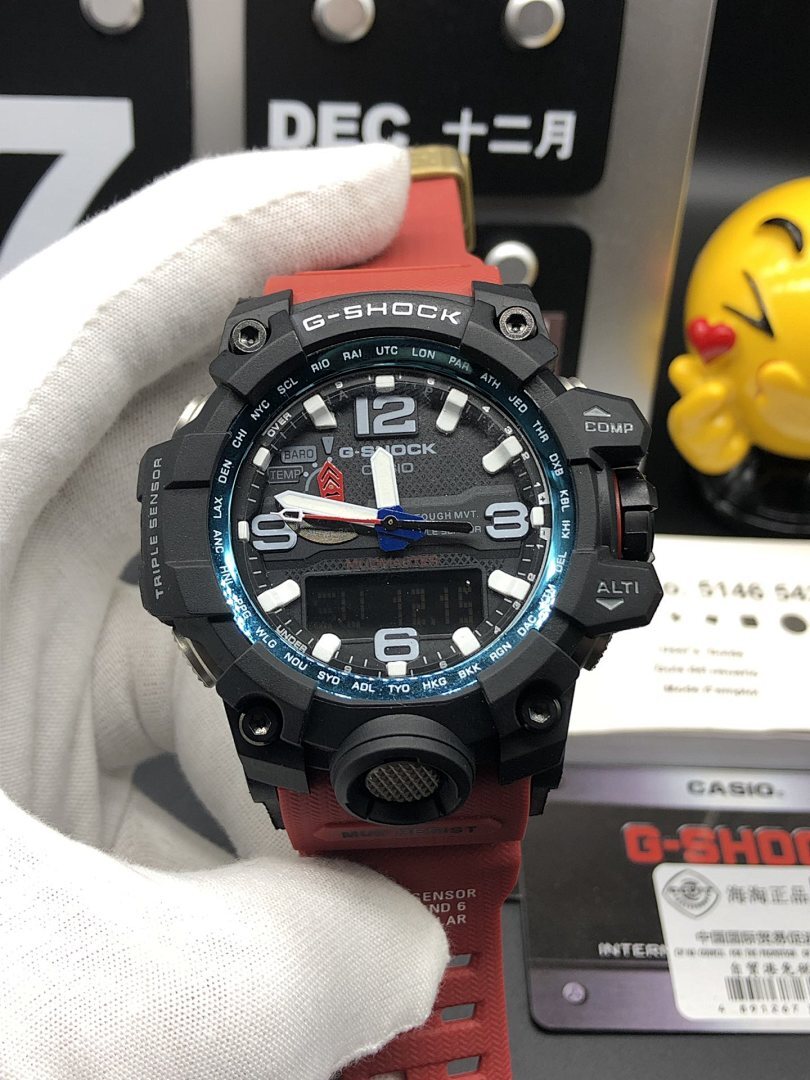 Casio G-Shock wristwatch front view with black case, red strap, and blue ring
