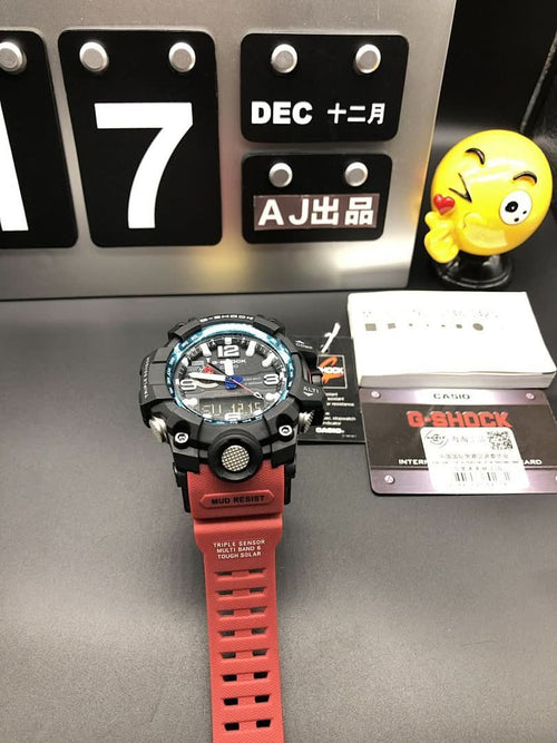 Casio G-Shock wristwatch with black case and red rubber strap, angled view