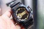 Casio G-Shock watch with dark strap and bezel, gold-accented dial, large digital display