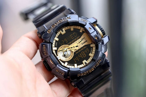 Casio G-Shock watch with dark strap and bezel, gold-accented dial, large digital display