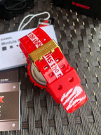 Red Casio G-Shock watch with gold-tone buckle and patterned strap, angled close view