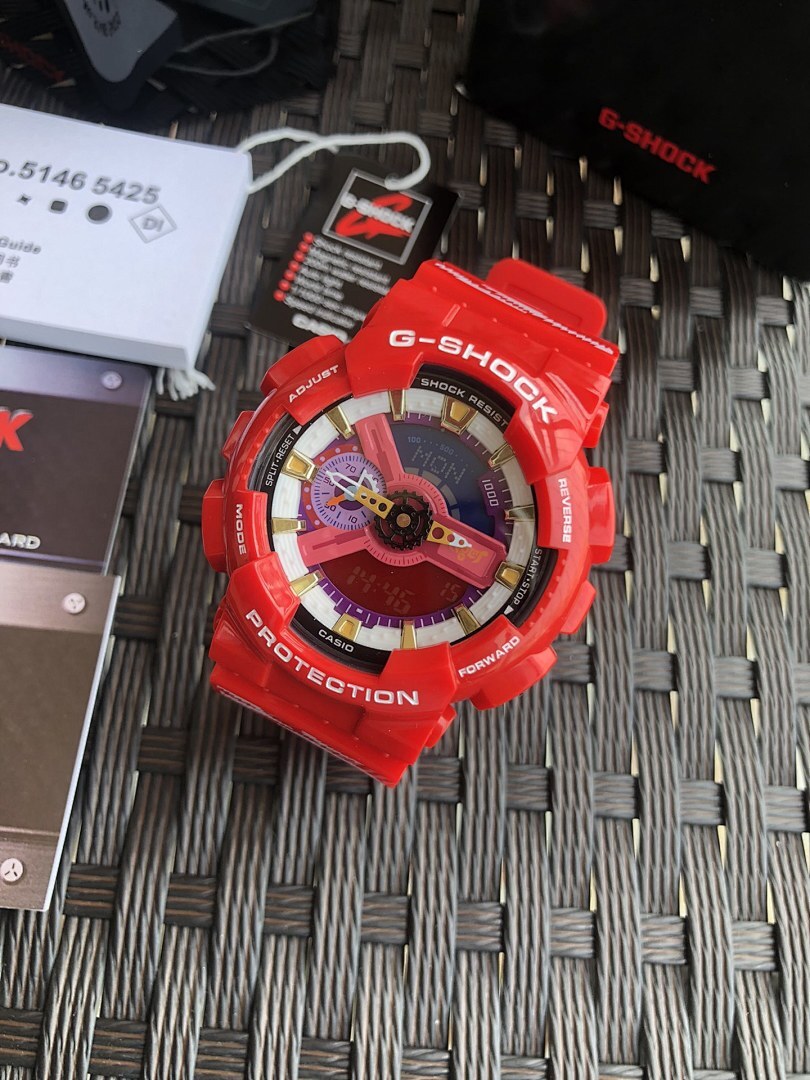 Red Casio G-Shock watch viewed from above, colorful dial on textured mat