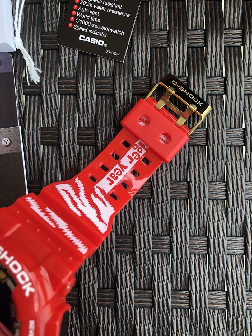 Red Casio G-Shock strap close-up with printed pattern and gold-tone clasp