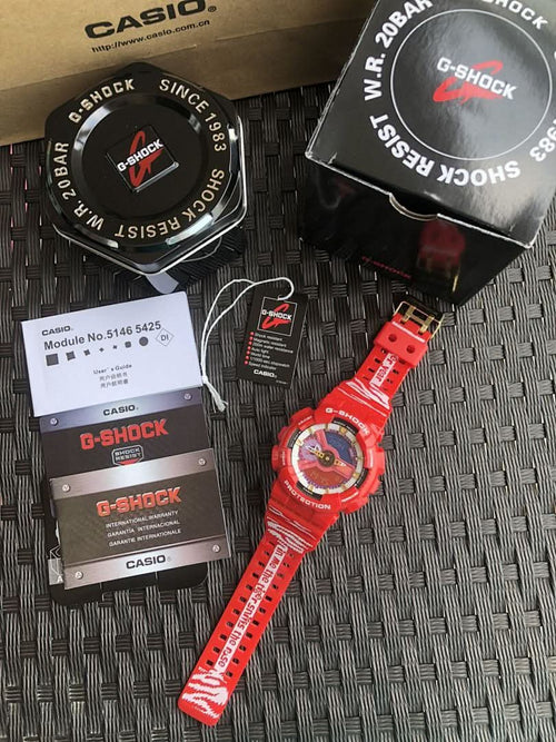 Casio G-Shock watch with red band and round dial, with retail boxes on mat