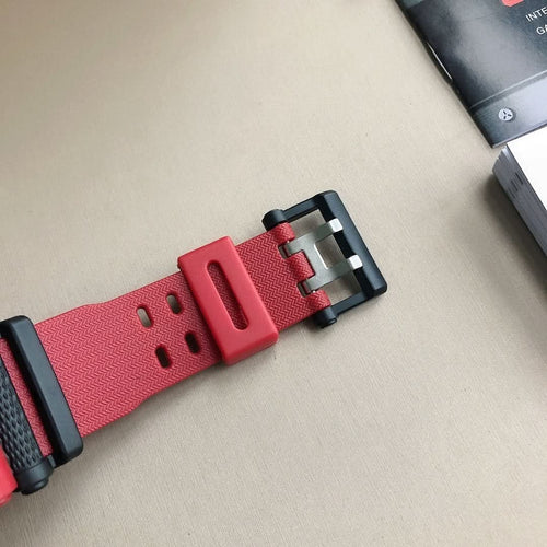 Red watch strap detail with black buckle and metal pin hardware.