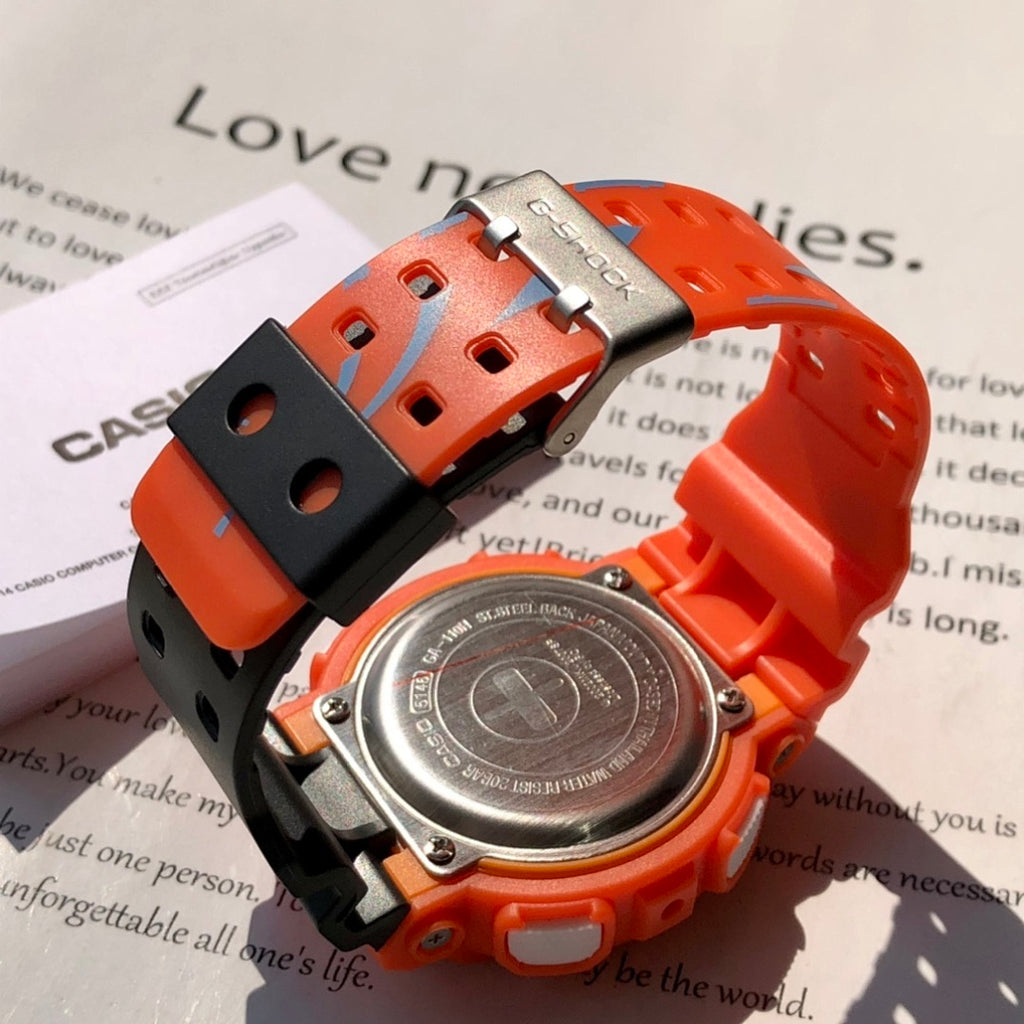 Casio G-Shock watch with orange resin strap and metal clasp, blue dial and gold ring