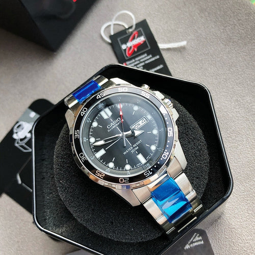 Casio watch with black dial, blue strap links, and silver metal case, on display box