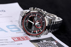 Casio watch with black dial, red subdials, and steel bracelet on paperwork