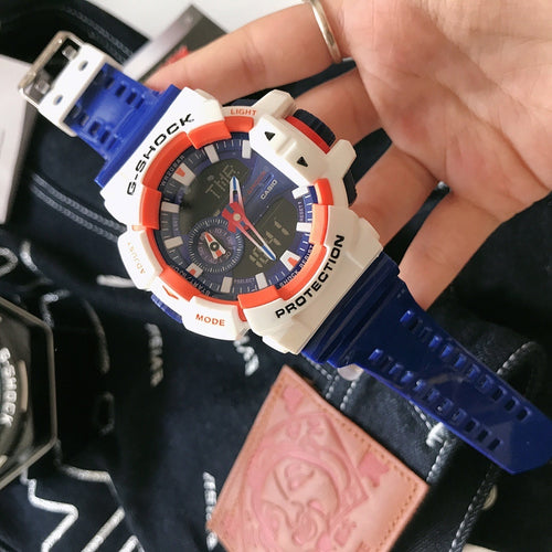 Casio G-Shock watch with blue silicone strap, white case, orange bezel accents